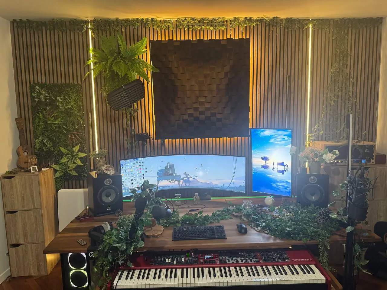 Le studio d'Elemental XII : mur de tasseaux en bois éclairé de lumière ambrée, diffuseur acoustique, plantes, écrans et Nord Stage 4 rouge.